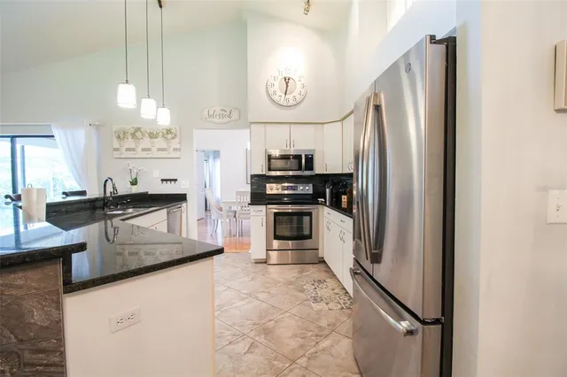 a kitchen with stainless steel appliances kitchen island granite countertop a refrigerator a stove and a sink