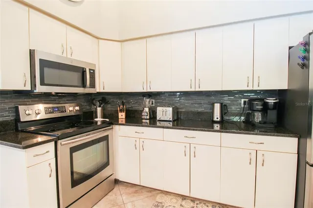 a kitchen with granite countertop stainless steel appliances a sink and cabinets