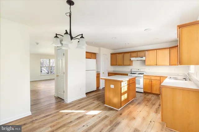 a large kitchen with stainless steel appliances granite countertop a sink a stove a refrigerator a center island with wooden floor and cabinets