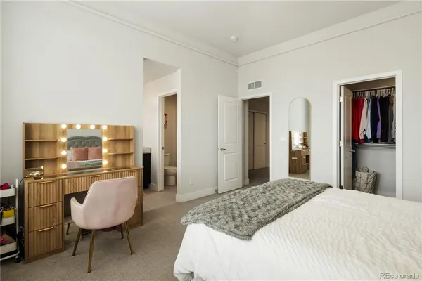 a bedroom with a bed a chair and potted plant on the table