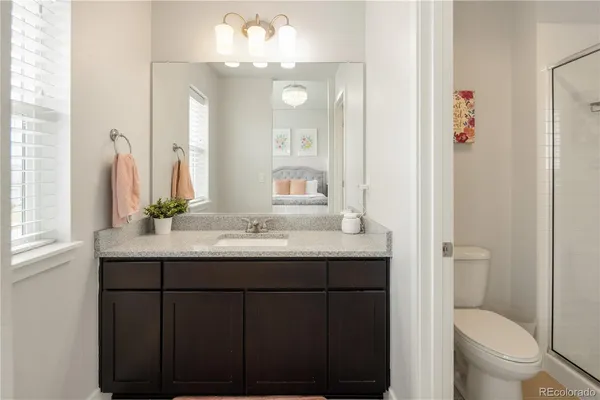a bathroom with a granite countertop sink a toilet and a mirror