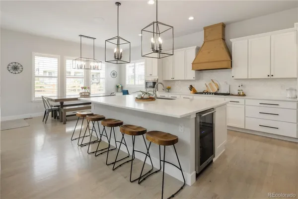 a open kitchen with granite countertop a stove a sink a dining table and chairs