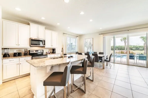 a kitchen with stainless steel appliances a stove a sink a dining table and chairs