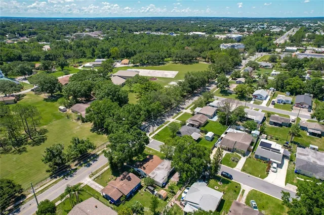 an aerial view of residential houses with outdoor space and trees