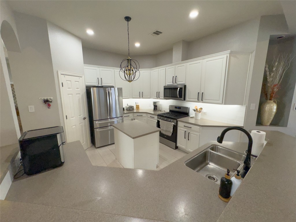 2410 Aspen Meadow Road Leander, TX 78641 - Photo 9 of 24 a kitchen with stainless steel appliances kitchen island granite countertop a refrigerator stove microwave and sink