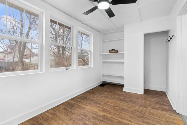 a view of an empty room with a window and wooden floor