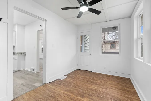 a view of an empty room with wooden floor and a window