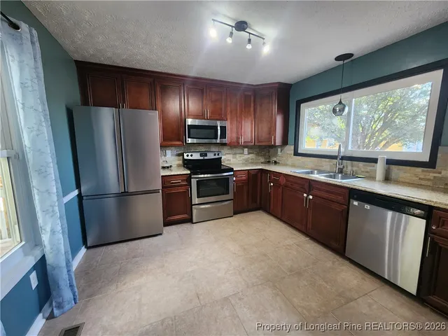 a kitchen with stainless steel appliances granite countertop a refrigerator a sink a stove a microwave a counter space and cabinets