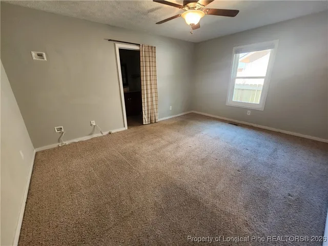 an empty room with chandelier fan and windows