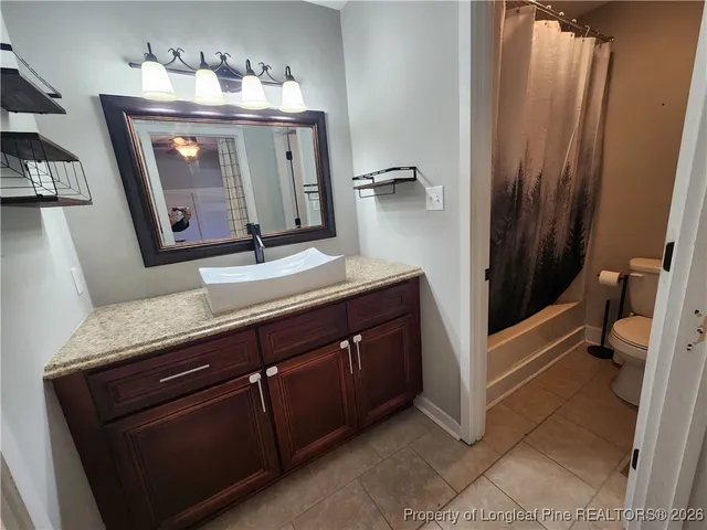 a bathroom with a granite countertop sink a mirror and a toilet