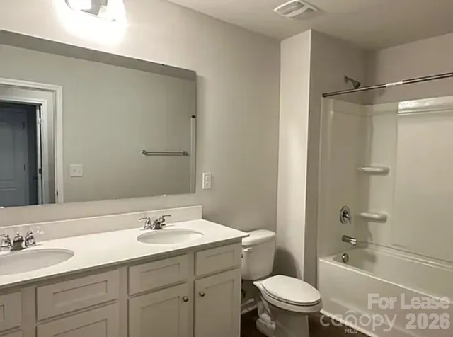 a bathroom with a granite countertop sink a toilet a mirror a bathtub and shower