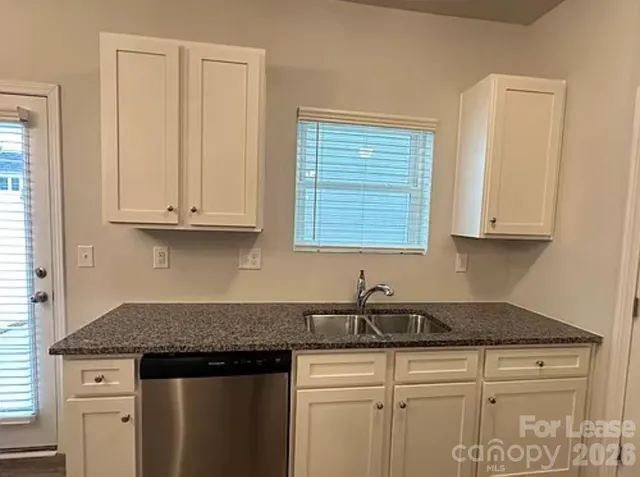 a kitchen with granite countertop a sink a stove and cabinets