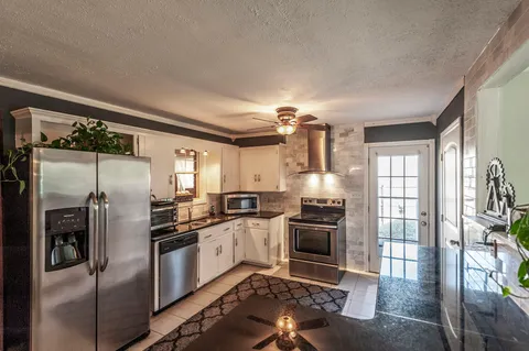 a kitchen with granite countertop a refrigerator stove and sink