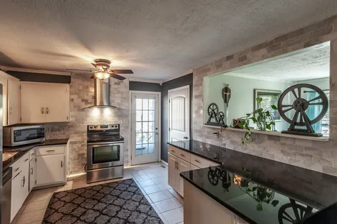 a kitchen with stainless steel appliances granite countertop a stove a sink and a microwave
