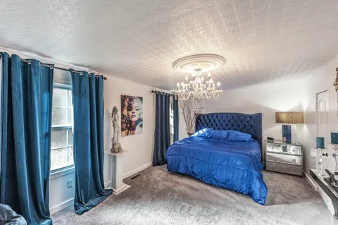 a bedroom with a large bed and a chandelier