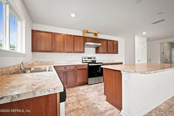 a kitchen with granite countertop a sink stove and refrigerator