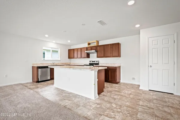 a kitchen with stainless steel appliances granite countertop a stove top oven a sink and a refrigerator