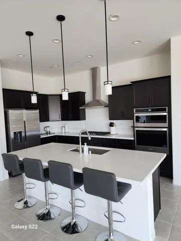 a kitchen with stainless steel appliances kitchen island a table chairs in it