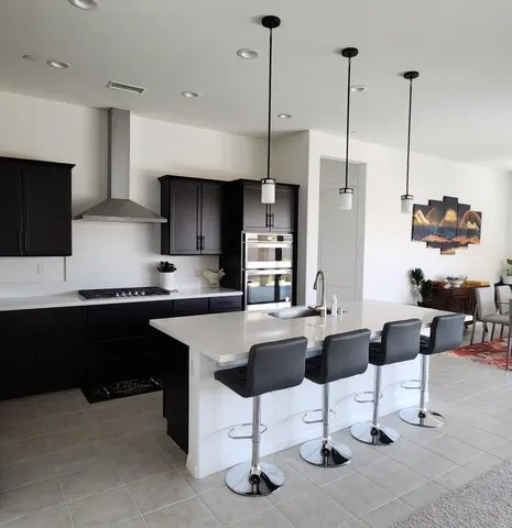 a kitchen with stainless steel appliances kitchen island granite countertop a stove a sink and a refrigerator