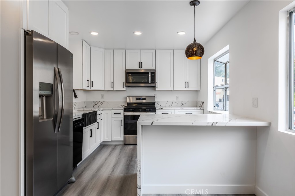 a kitchen with kitchen island white cabinets and stainless steel appliances
