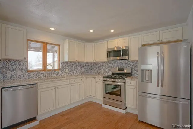a kitchen with white cabinets stainless steel appliances and a window