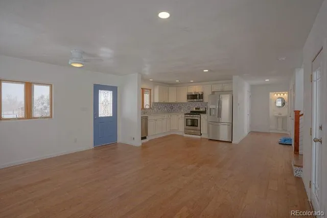 a view of empty room with kitchen and window