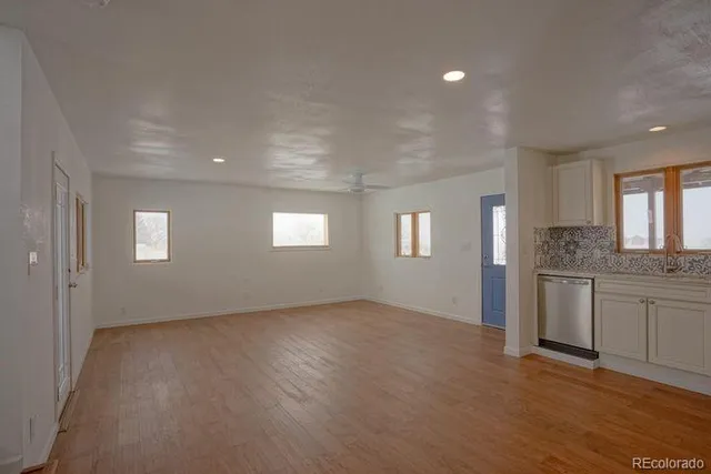 a view of an empty room with window and wooden floor
