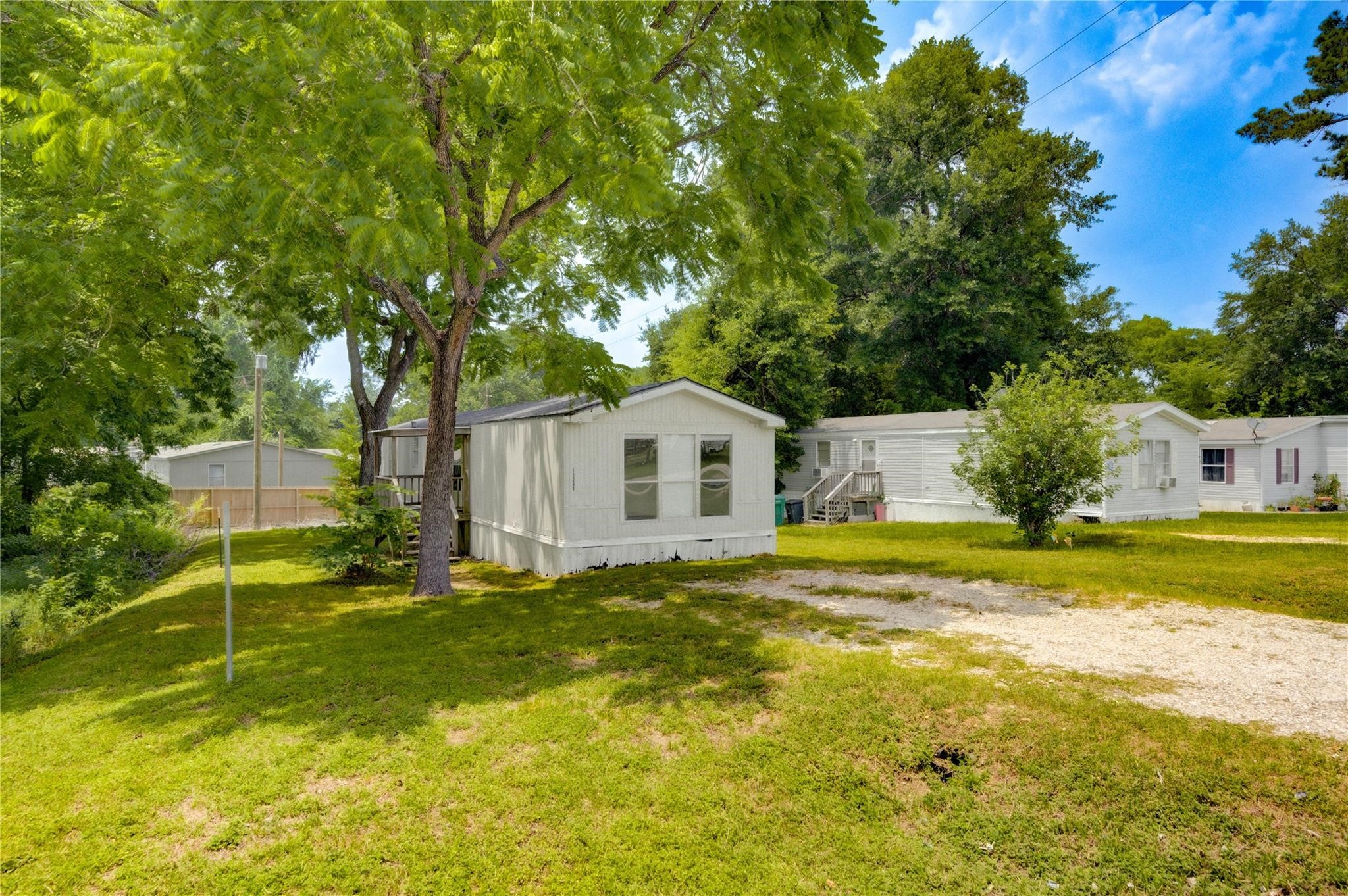 13265 Pecan Tree Drive Willis, TX 77318 - Photo 2 of 19 a white house with a big yard plants and large trees