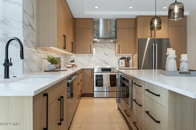 a kitchen with stainless steel appliances granite countertop a sink and a refrigerator