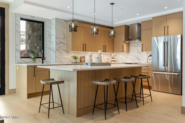 a kitchen with kitchen island a dining table chairs sink and white cabinets