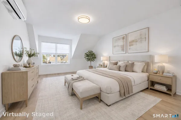 a spacious bedroom with a bed a mirror and a large window