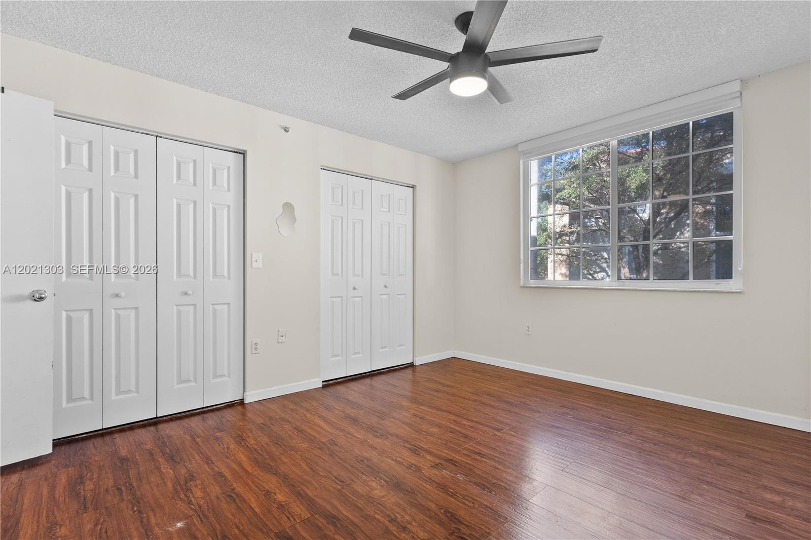 2123 Renaissance Boulevard, Unit 201 Miramar, FL 33025 - Photo 13 of 22 an empty room with wooden floor chandelier fan and windows
