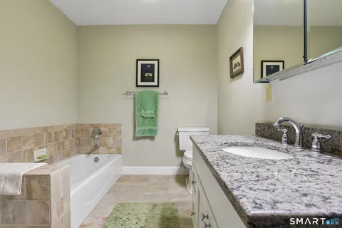 a bathroom with a granite countertop sink a bathtub and next to a window
