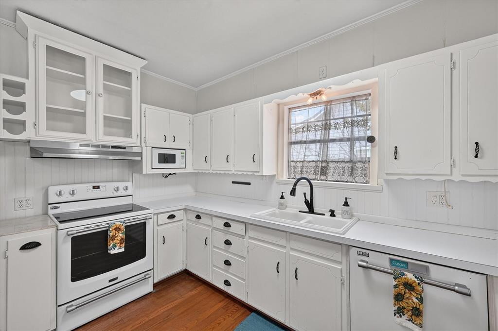 304 East Main Street Itasca, TX 76055 - Photo 15 of 38 Kitchen featuring white cabinetry, a double basin sink with a matte black faucet, a white electric range, a built-in microwave, and wood-finish flooring