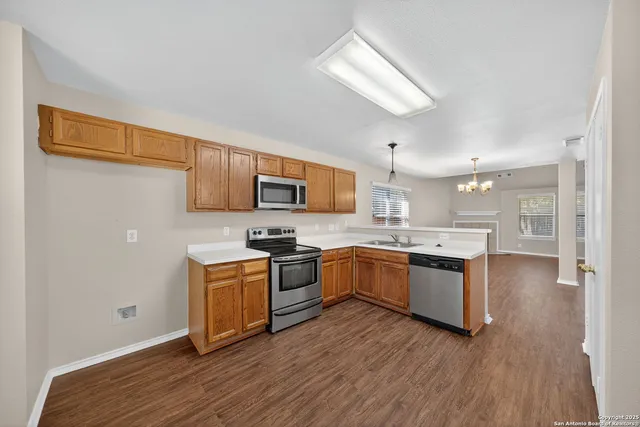 a kitchen with stainless steel appliances granite countertop a stove top oven a sink dishwasher a refrigerator and cabinets with wooden floor