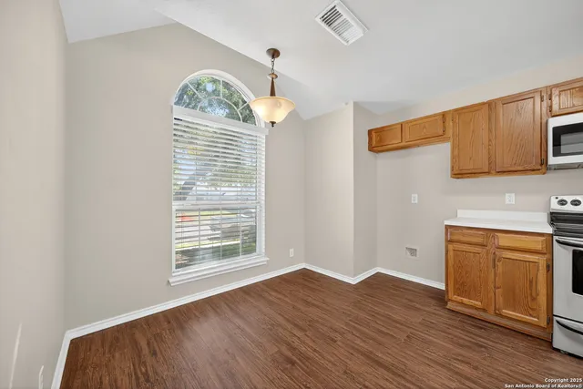 a view of an empty room with window and wooden floor
