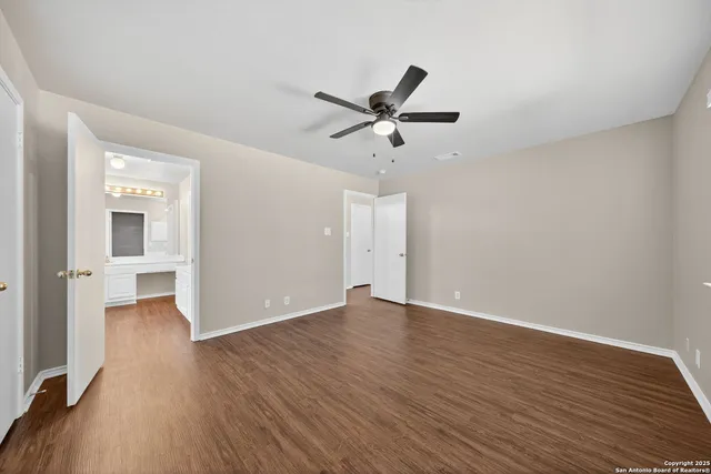 an empty room with wooden floor and ceiling fan