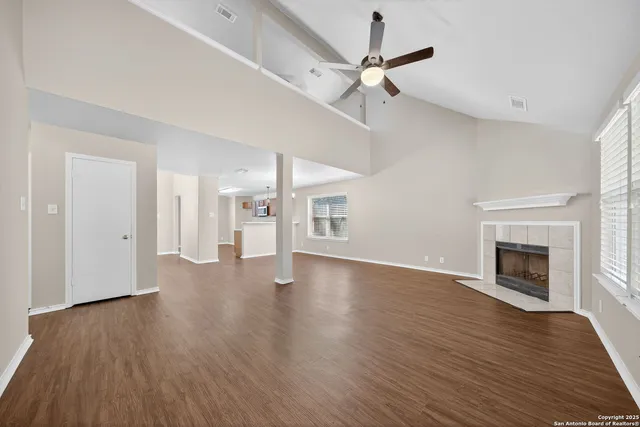 a view of an empty room with wooden floor fireplace and a window