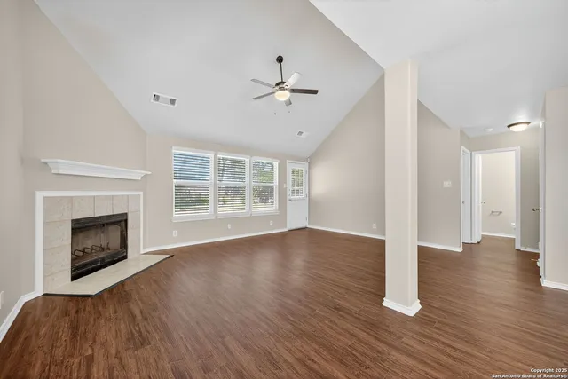 a view of an empty room with wooden floor fireplace and a window