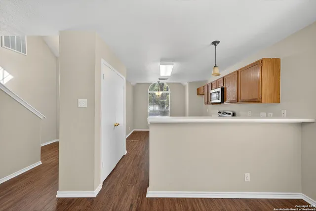 a view of a kitchen with kitchen island a sink wooden floor and a refrigerator