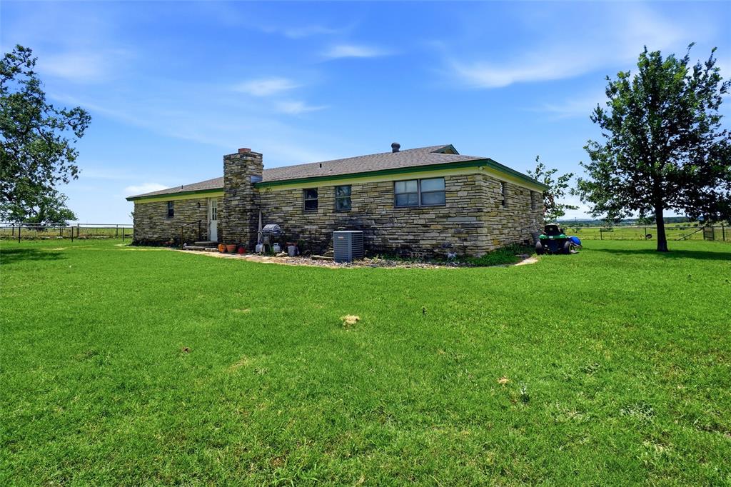 2186 Gilliland Road Springtown, TX 76082 - Photo 15 of 25 Stone-clad exterior featuring a prominent chimney, green roof trim, and multiple windows