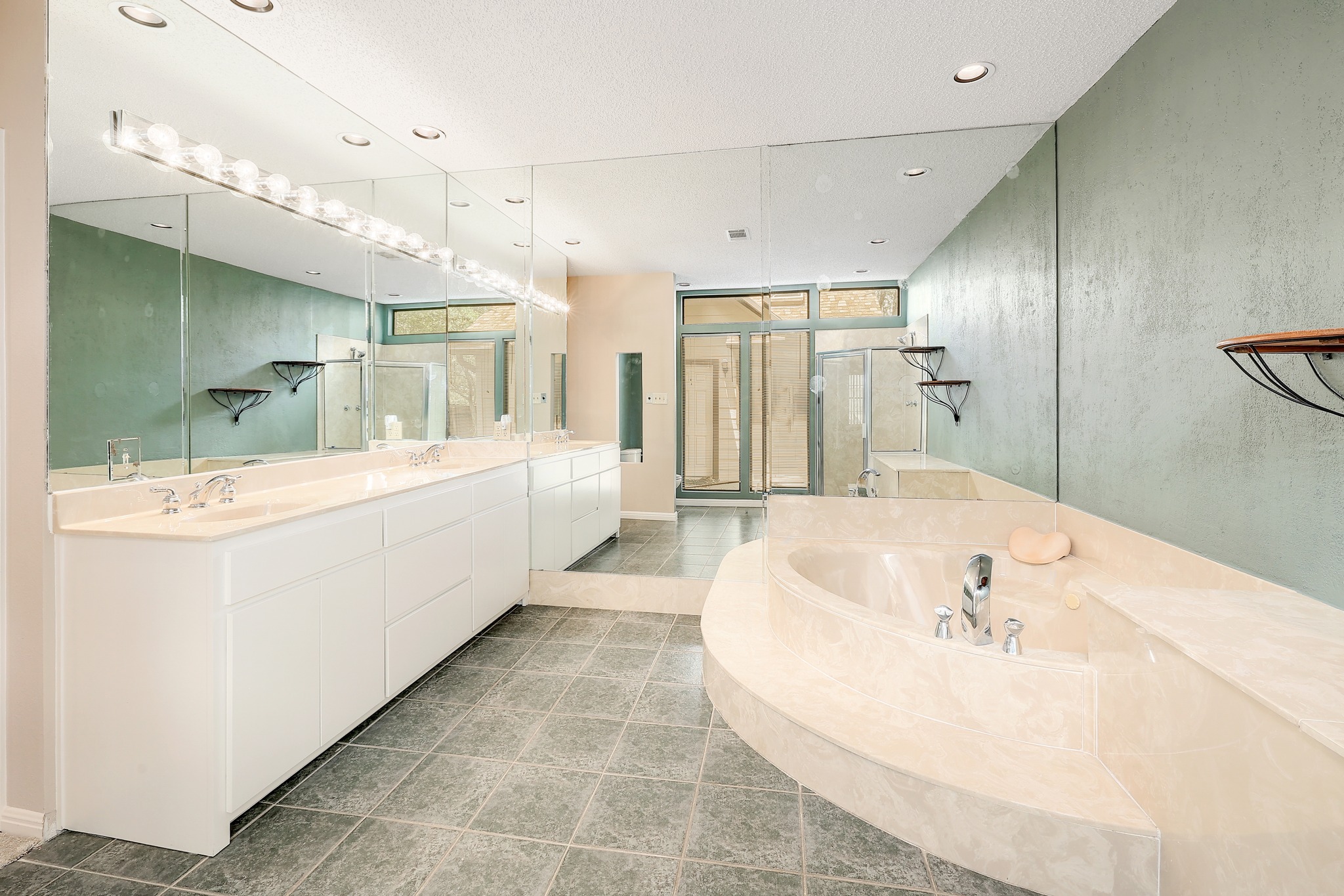 2202 Warfield Way Austin, TX 78728 - Photo 17 of 32 A generously sized primary bathroom features dual vanities and a deep soaking tub, all set within a mirror-paneled interior.