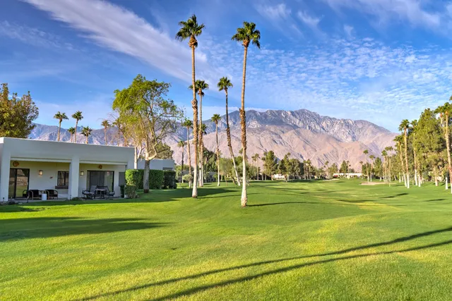 a front view of a house with a garden and trees