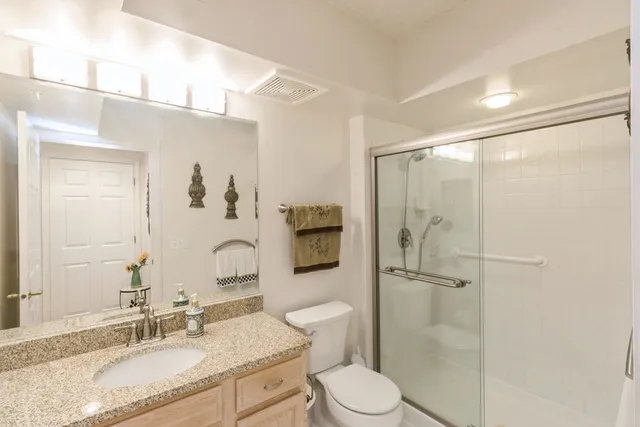 a bathroom with a granite countertop sink toilet and shower