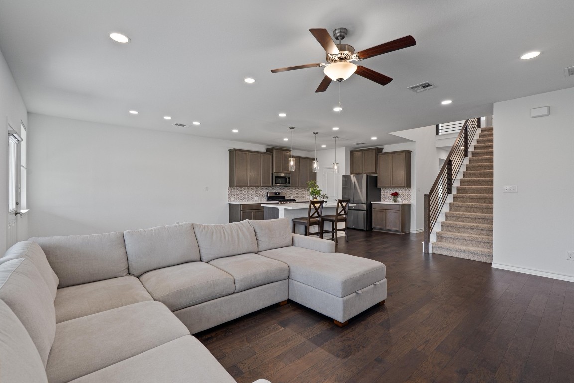 a living room with furniture and kitchen view with wooden floor