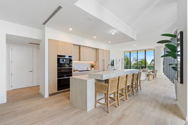 a kitchen with stainless steel appliances kitchen island granite countertop a table chairs and a refrigerator