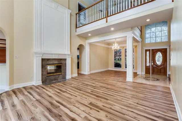a view of an empty room with wooden floor fireplace and a window
