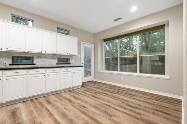 a kitchen with granite countertop a stove a sink and white cabinets with wooden floor