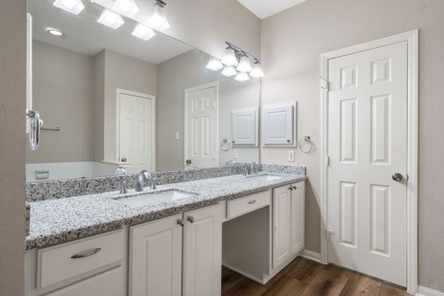 a bathroom with a granite countertop double vanity sink a mirror and a