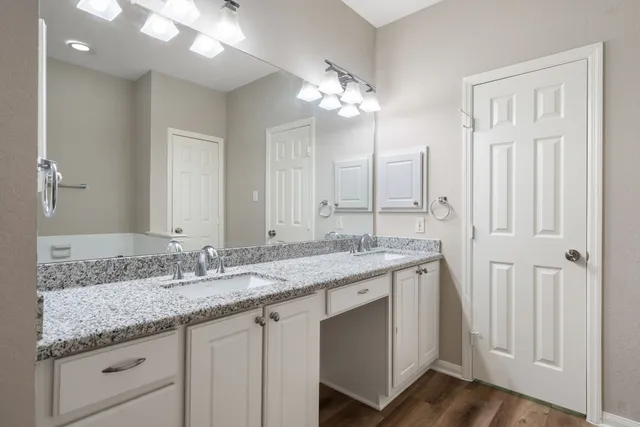 a bathroom with a granite countertop double vanity sink a mirror and a